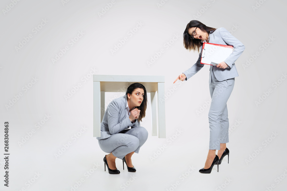 Need a rescue. Young woman under pressure from the colleague. Hiding under the table while woman's screaming. Concept of office worker's troubles, business or problems with mental health. Need a rescue. Young woman under pressure from the colleague. Hiding under the table while woman's screaming. Concept of office worker's troubles, business or problems with mental health.