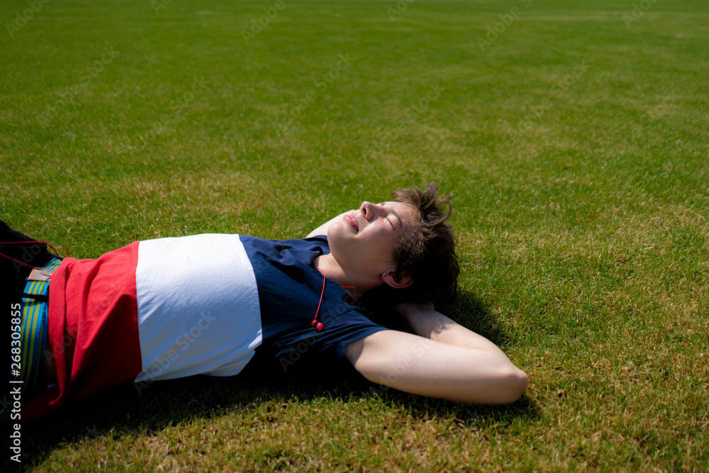 young man relax chill outdoor on the green grass lawn under the summer sunshines young man relax chill outdoor on the green grass lawn under the summer sunshines