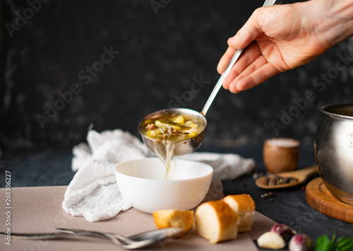 Canvastavla chefs hand pour fresh hot soup in a white empty bowl, food preparations