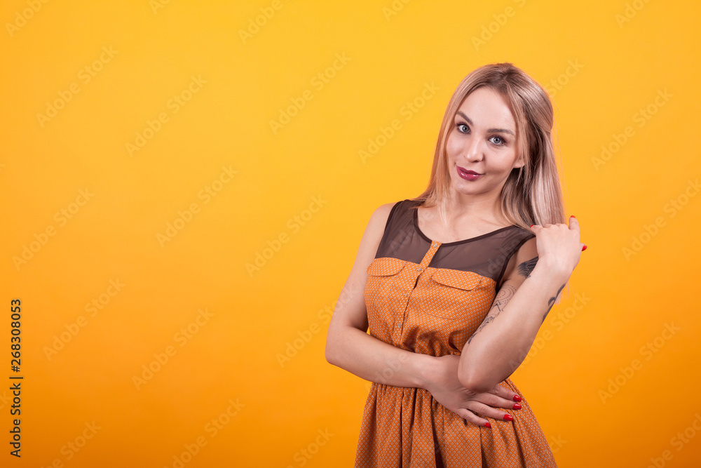 Obraz premium Pretty young woman smilling at the camera in casual dress over yellow background