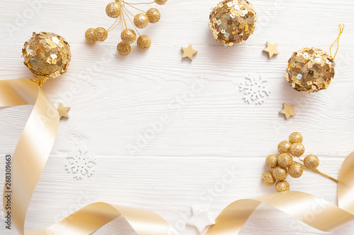 Christmas background for greeting card with place for text. x-mas golden toys and beige ribbon on wooden background. Flat lay, top view photo mockup