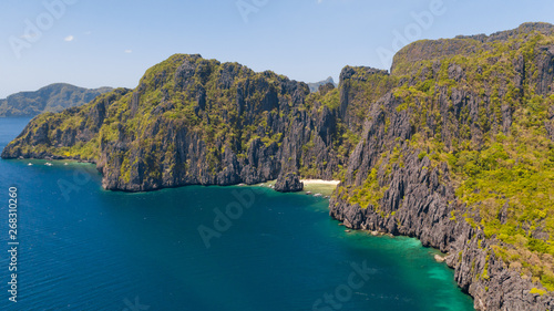 Rocky coast with a white beach. Tropical island with jungle. El Nido Palawan National Park Philippines. White sand beach and turquoise lagoon.