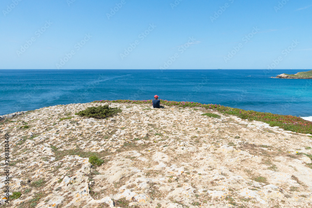 una persona seduta davanti all'oceano contempla