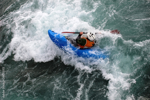An experienced canoeist paddles while partially submerged in white water rapids.