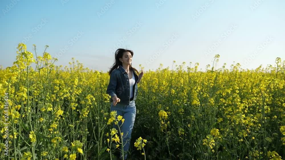 Cheery girl with flying hair running in a rapeseed field in summer in slo-mo Cheery girl with flying hair running in a rapeseed field in summer in slo-mo