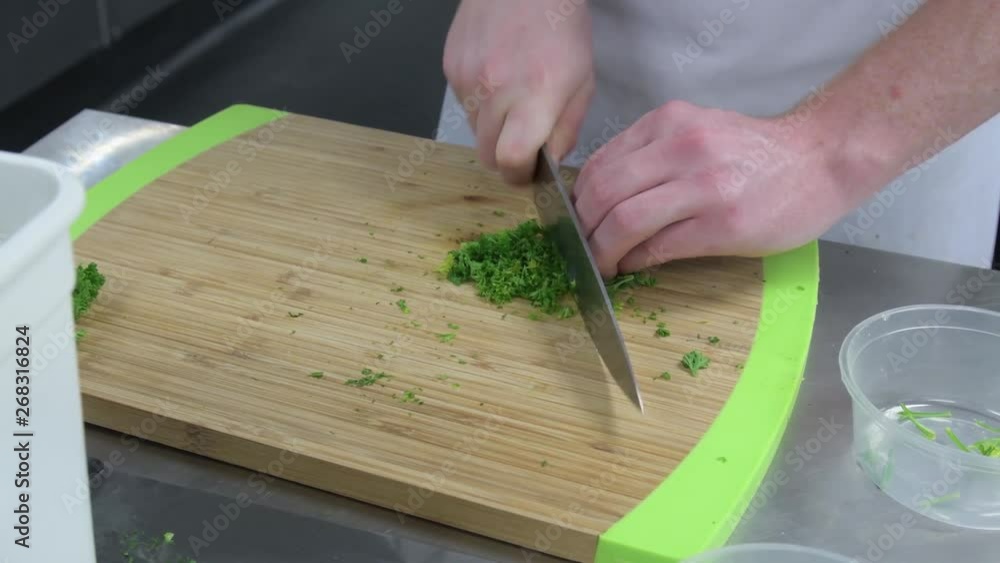 Chefs hands chopping coriander on wooden board for meal preparation Chefs hands chopping coriander on wooden board for meal preparation