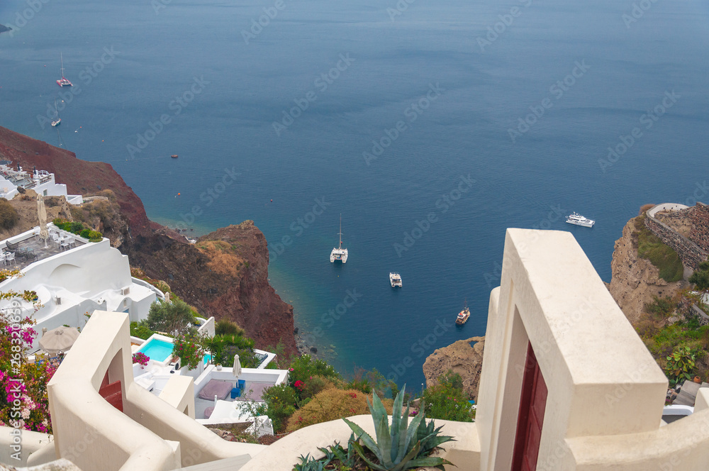 Fototapeta Houses and terraces of the village of Oia above a bay with red cliffs