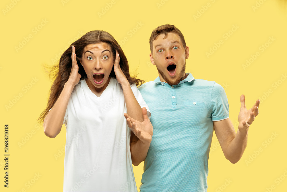 Beautiful young couple's half-length portrait on yellow studio background. Woman and man in shirts astonished or shocked of something. Facial expression, human emotions concept. Trendy colors. Beautiful young couple's half-length portrait on yellow studio background. Woman and man in shirts astonished or shocked of something. Facial expression, human emotions concept. Trendy colors.