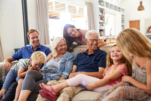 Foto Multi-Generation Family Sitting On Sofa At Home Relaxing And Chatting