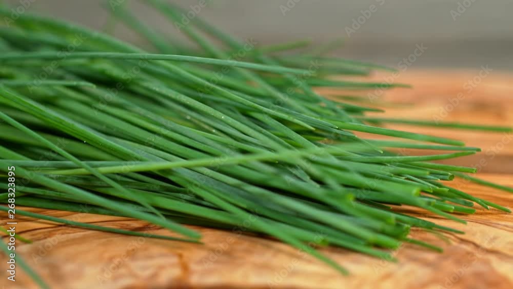 Super Slow Motion Shot of Fresh Chive Falling on Wooden Cutting Board at 1000fps. Super Slow Motion Shot of Fresh Chive Falling on Wooden Cutting Board at 1000fps.