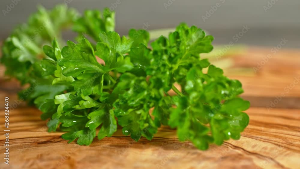 Super Slow Motion Shot of Fresh Parsley Falling on Wooden Cutting Board at 1000fps. Super Slow Motion Shot of Fresh Parsley Falling on Wooden Cutting Board at 1000fps.