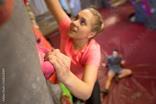 fitness, extreme sport, bouldering, people and healthy lifestyle concept - young woman exercising at indoor climbing gym