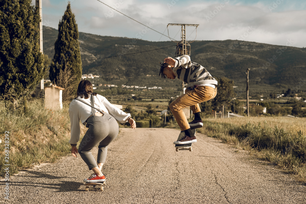 Obraz premium Trendy young couple having fun with a skateboard on the road