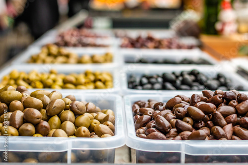 Assortment of olives on the marketplace. Rows of different types of olives in transparent plastic bowls.