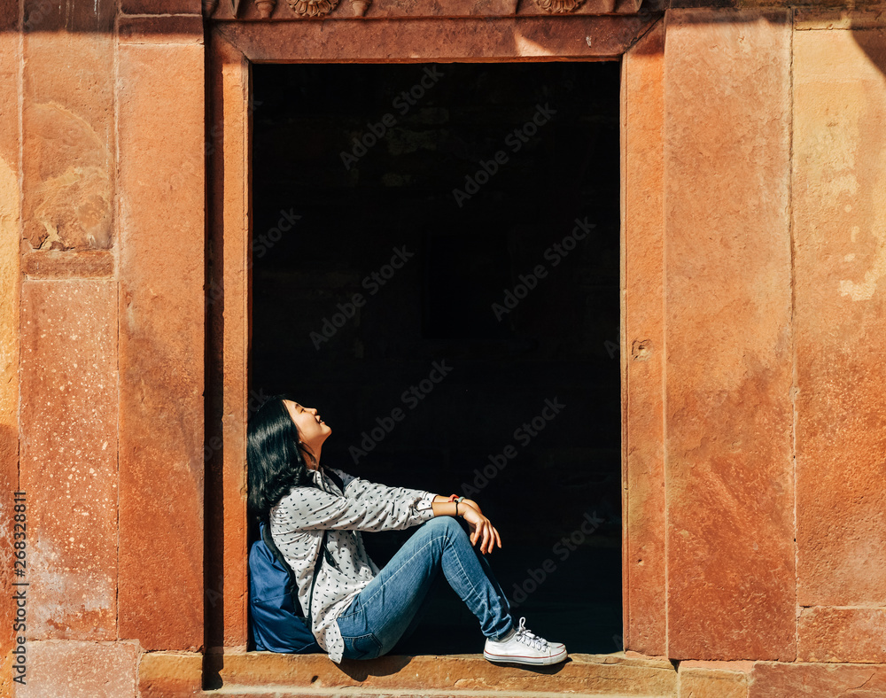 single young woman resting on doorstep at Fatehpur Sikri, India