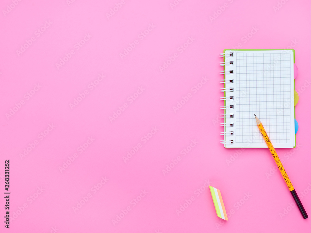 top view of the table of a teenage child, the composition of a notebook pencil eraser on a pink background top view of the table of a teenage child, the composition of a notebook pencil eraser on a pink background