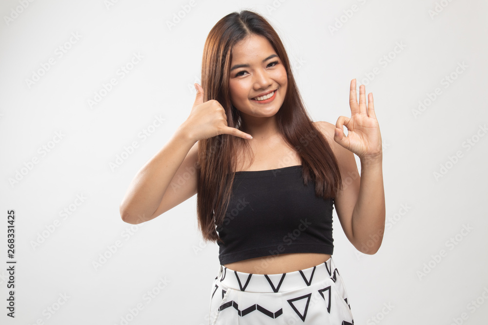 Young Asian woman show with phone gesture and OK sign. Young Asian woman show with phone gesture and OK sign.