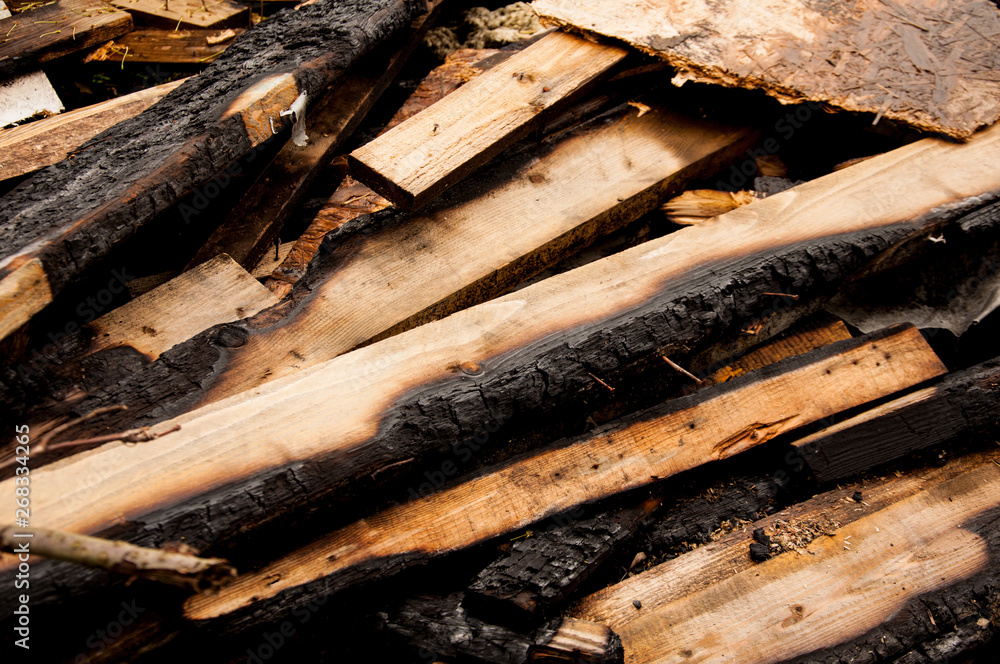 The charred boards lie on a pile. Many old boards The charred boards lie on a pile. Many old boards