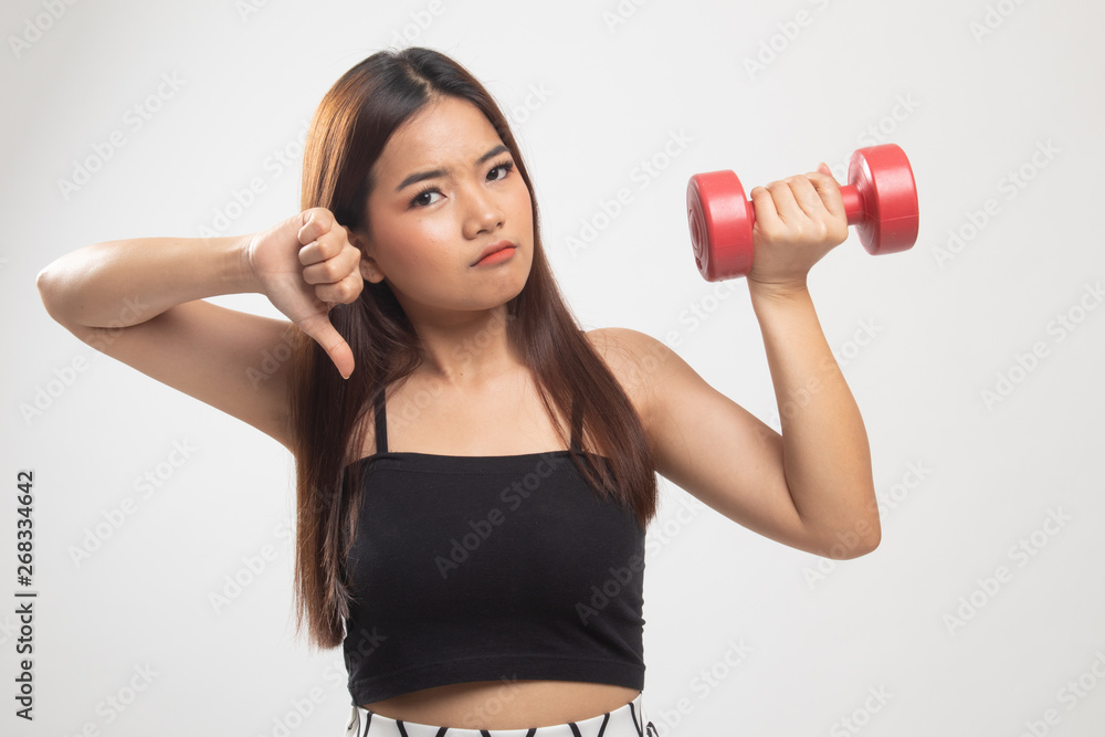 Unhappy Asian woman thumbs down with dumbbells. Unhappy Asian woman thumbs down with dumbbells.