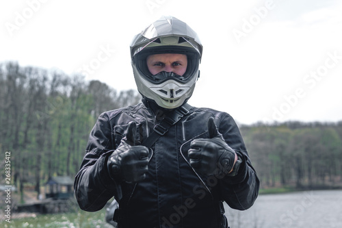 Motorcyclist man is two hands take like. Off road. Motorcycle trip. enduro Traveling, Lifestyle Travel dual sport outdoor concept. clothing with protection, forest background