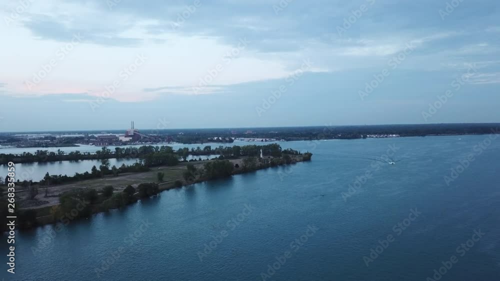 Belle Isle Detroit aerial view at sunset on a summer day. Bridge, buildings, boats visible in the distance. Island silhouette on the Detroit river with the Detroit skyline in the background. Belle Isle Detroit aerial view at sunset on a summer day. Bridge, buildings, boats visible in the distance. Island silhouette on the Detroit river with the Detroit skyline in the background.
