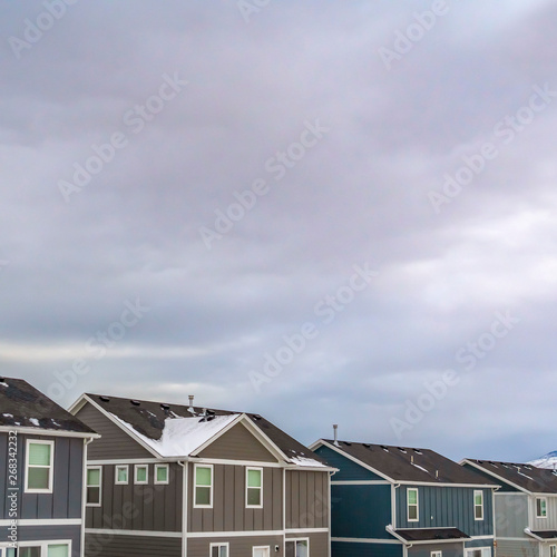 Square Lovely homes with snow capped mountain and cloud filled sky in the background