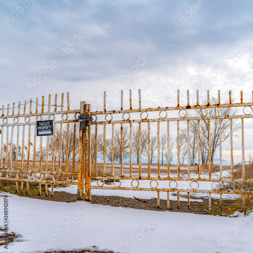 Square Private property with a No Trespassing sign on the rusty gate viewed in winter