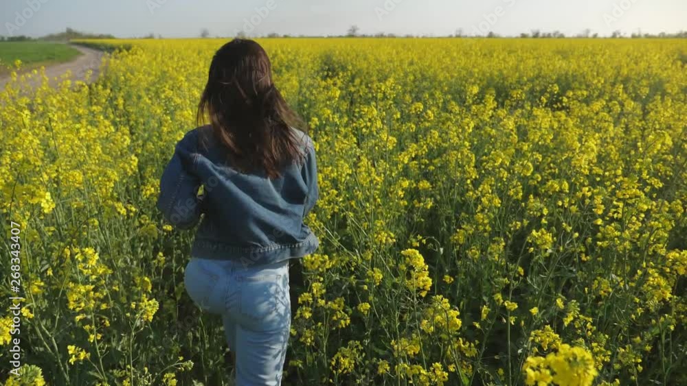 Young woman with waving hair running in a rapeseed field in summer in slo-mo Young woman with waving hair running in a rapeseed field in summer in slo-mo