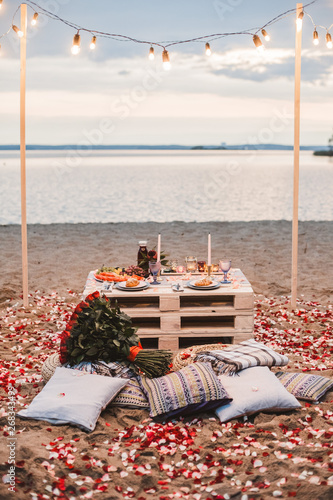 Romantic dinner  at the beach concept. Romantic dinner served for two on the sea beach with candles and wine.