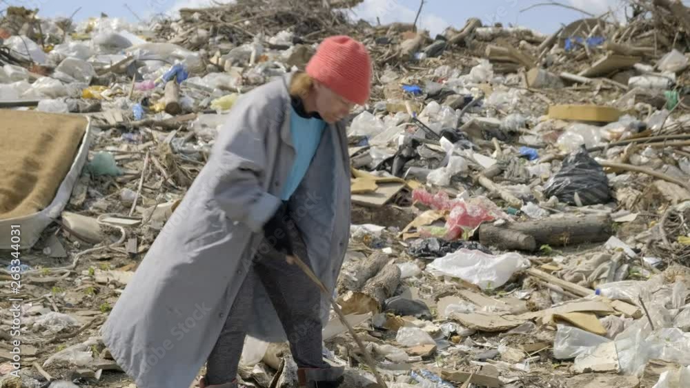 beggar hungry person rummaging in a pile of garbage at a city dump. Poverty, social problem, unemployment. beggar hungry person rummaging in a pile of garbage at a city dump. Poverty, social problem, unemployment.