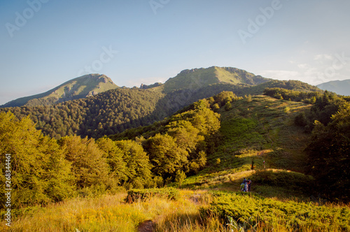 Panorama of the mountain with hikers on the path at golden hour