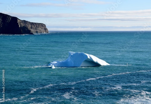 iceberg floating in the ocean near a cliff