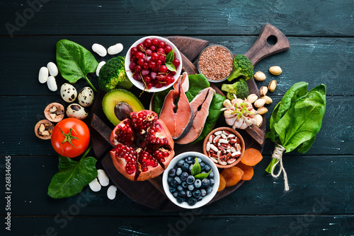 Healthy food: Fish, blueberries, nuts, pomegranate, avocados, tomatoes, spinach, flax. Concept of Dietary Nutrition. Top view. photo
