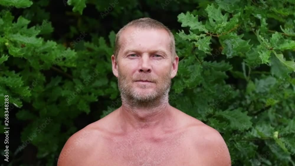 Portrait of an adult man against the backdrop of a green forest. Forester close up. White unshaven man looking at the camera. Portrait of an adult man against the backdrop of a green forest. Forester close up. White unshaven man looking at the camera.