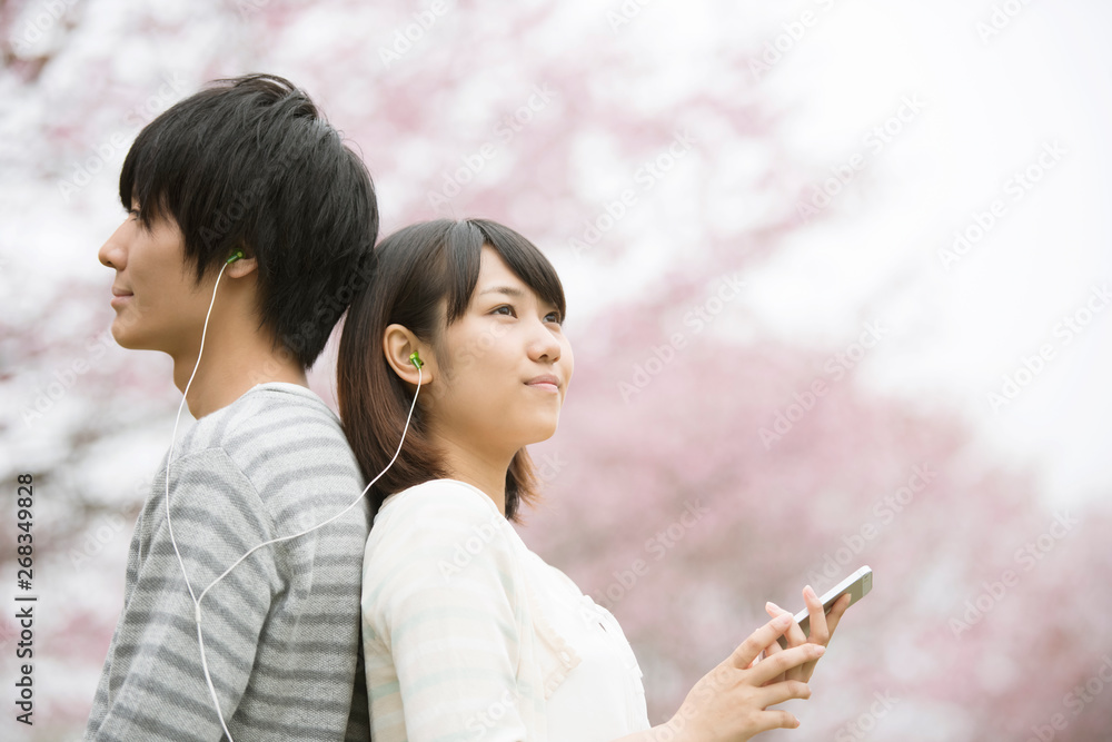 Fototapeta premium 桜の前で音楽を聴くカップル