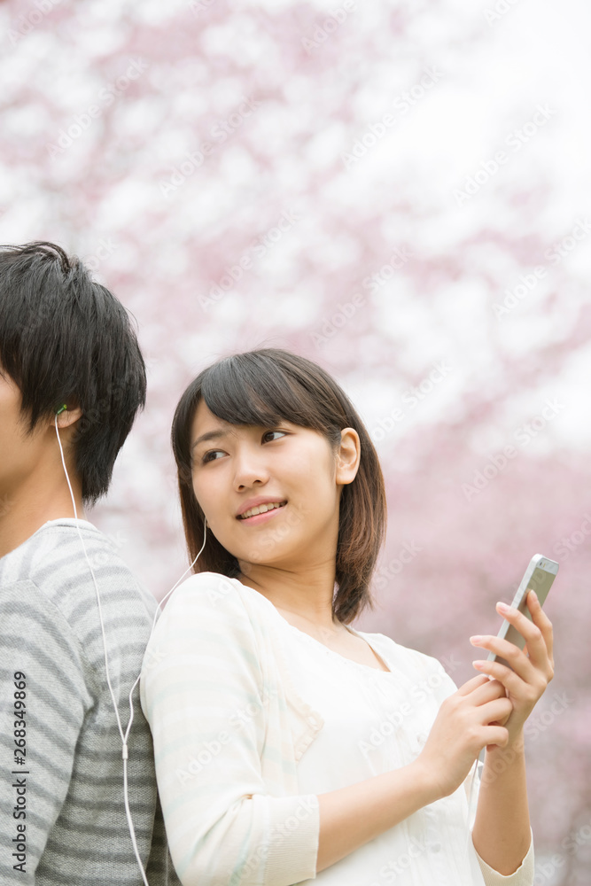 桜の前で音楽を聴くカップル