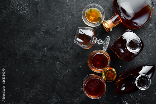 Fotografi A bottle of cognac and glasses on a black background