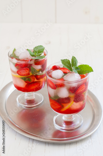 Summer cold drink . Lemonade with mint and strawberries on a light background.