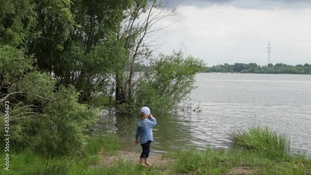 little boy walks along the river. the child runs around the lake. slow motion. happy baby playing near the water. little boy walks along the river. the child runs around the lake. slow motion. happy baby playing near the water.