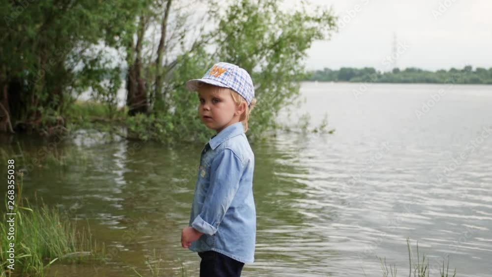 little boy walks along the river. the child runs around the lake. slow motion. happy baby playing near the water. little boy walks along the river. the child runs around the lake. slow motion. happy baby playing near the water.