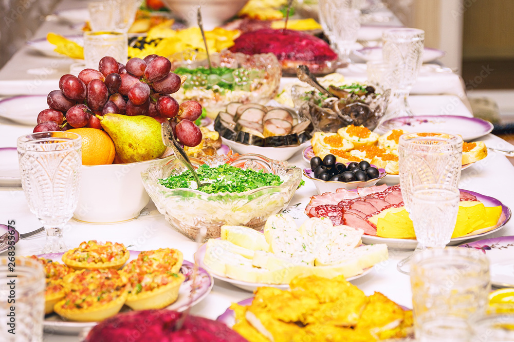 Fototapeta premium Served table. Snacks, fruits, sandwiches, salads, caviar and slicing on the holiday table. Selective focus