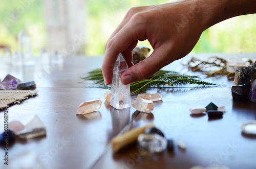Beautiful Clear Quartz, variety of crystal on wood table. Bright Quartz crystal, healing crystal being held in hand. Woman holding quartz tower, crisp colors in natural lighting. Vibrant meditation.