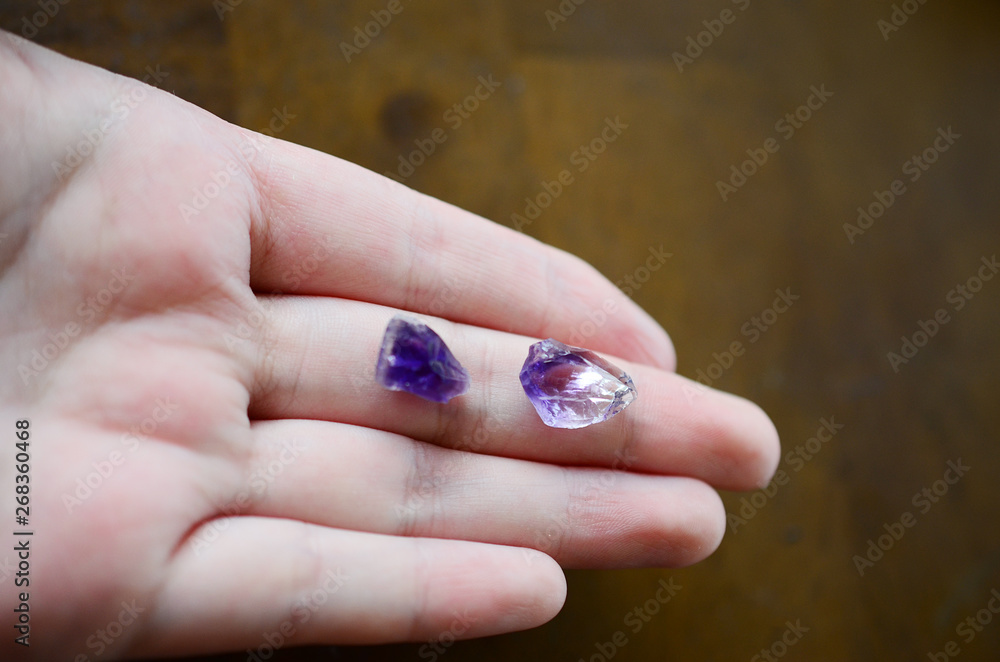 Tiny amethyst crystals being held in woman's hand, miniature crystal chips. Macro photo in natural lighting, deep purple healing crystal. Micro minerals, crisp colors. Tiny amethyst crystals being held in woman's hand, miniature crystal chips. Macro photo in natural lighting, deep purple healing crystal. Micro minerals, crisp colors.
