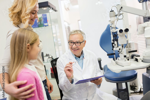 Likable eye specialist gives eye glasses to child