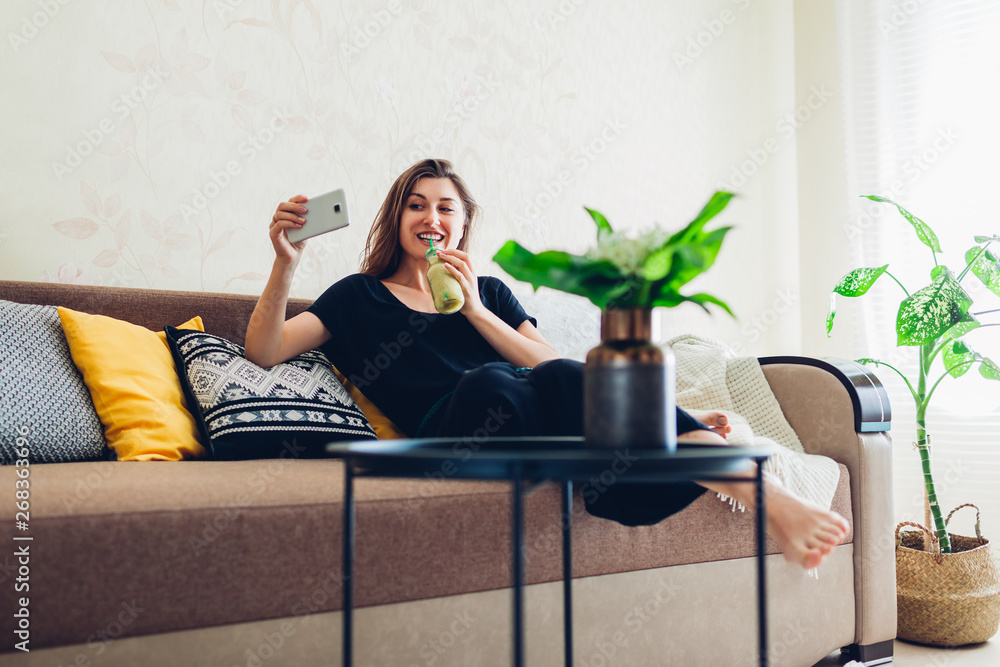 Young woman relaxing in living room and drinking smoothie. Healthy diet Young woman relaxing in living room and drinking smoothie. Healthy diet
