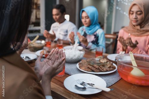 Hijab women and a man pray together before meals  a fast breaking meal served on a table in backyard