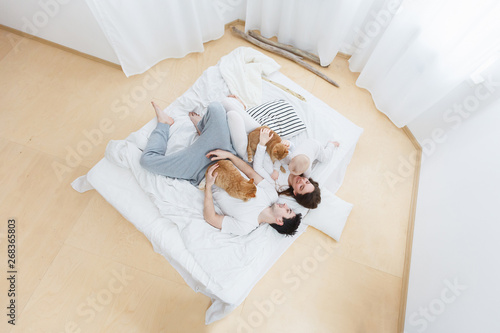 Young parents have fun with their baby, happy family at home. Top view-portrait of loving parent playing with their kid. Warm and cozy scene in real life interior. Lifestyle photo. 