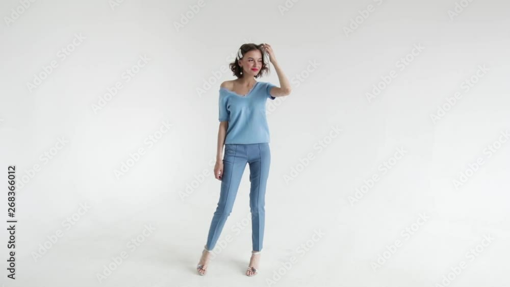 Model beautiful woman with short hair posing in the Studio on a white background in a blue jumper and blue pants Model beautiful woman with short hair posing in the Studio on a white background in a blue jumper and blue pants