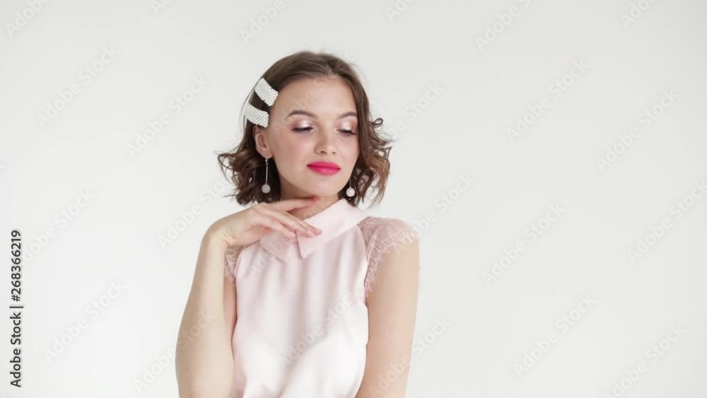 Beautiful brunette girl model with short hair on white background in white blouse posing in Studio. Slow mo Beautiful brunette girl model with short hair on white background in white blouse posing in Studio. Slow mo