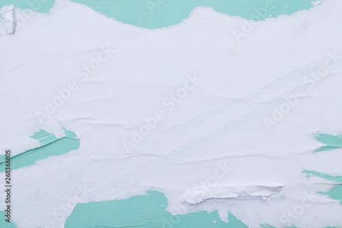 White and turquoise sheets of torn paper pasted on the wall.